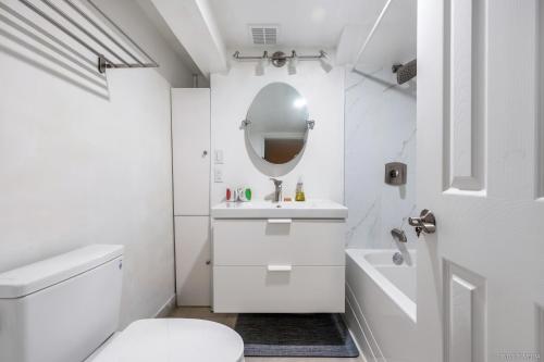 bagno bianco con lavandino e specchio di Deluxe Basement with Private Bedroom - R1 / R3 a Vancouver