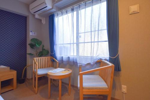 um quarto com duas cadeiras, uma mesa e uma janela em Hotel Neiraku em Nara