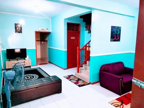 a living room with a couch and a red door at ILHAM HOMESTAY Taman Sejati Mile 7 in Sandakan