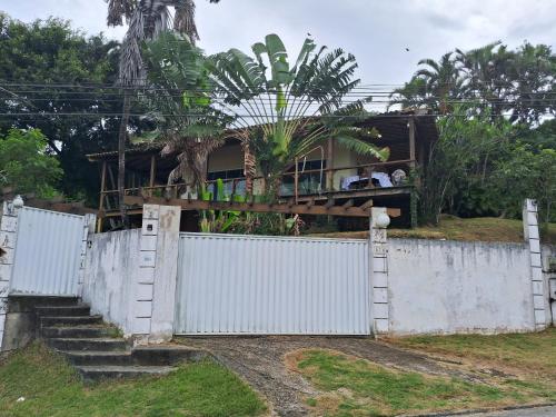 een huis achter een wit hek met een hek bij Casa da Praia em Costazul in Rio das Ostras