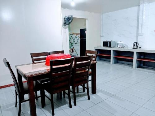 a dining room with a table and chairs and a kitchen at ILHAM HOMESTAY Taman Sejati Mile 7 in Sandakan