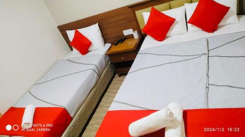 two beds in a hotel room with red pillows at Hotel Casa Reo in Kampong Bagan Lalang