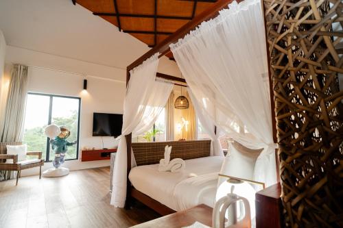 a bedroom with a canopy bed with white drapes at Nacpan Beach Resort Managed by H Hospitality Group in El Nido