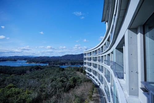 a building with a view of a river and mountains at Shima Kanko Hotel The Bay Suites in Shima
