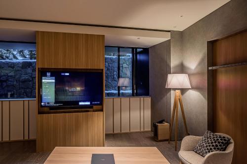 a living room with a tv and a couch and a chair at MUWA NISEKO in Kutchan