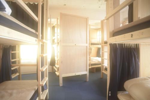 a dorm room with bunk beds and a closet at Wharf Inn in Yokohama