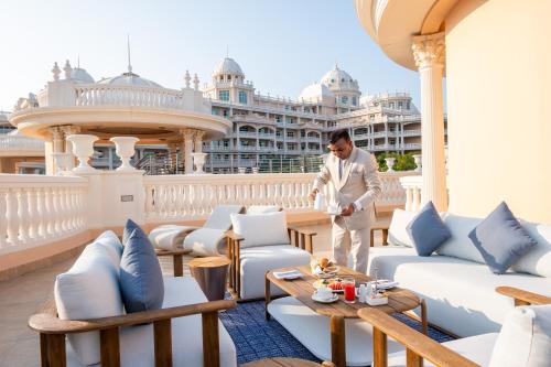 a man standing on a balcony with chairs and tables at Kempinski Hotel & Residences Palm Jumeirah in Dubai