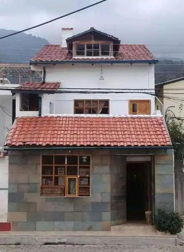 ein weißes Haus mit rotem Dach in der Unterkunft La casa del Árbol in Quito