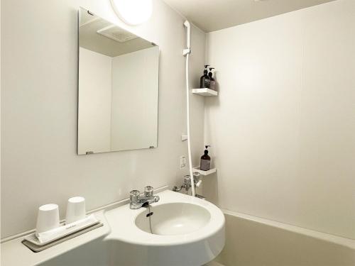 a white bathroom with a sink and a mirror at CHECKinn Osaka Shinimamiya in Osaka
