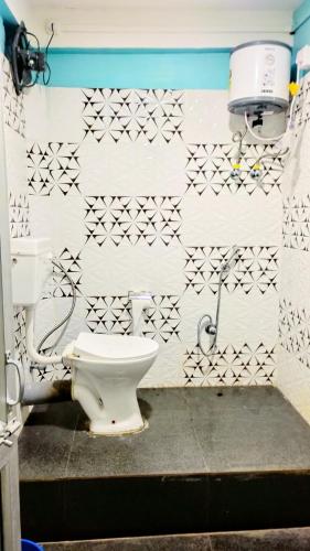 a bathroom with a toilet and a white wall at The PugMark Wildlife Resort in Jyoti Gaon