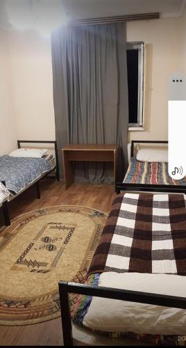 una camera con due letti e un tappeto sul pavimento di ДОМ Hostel a Almaty