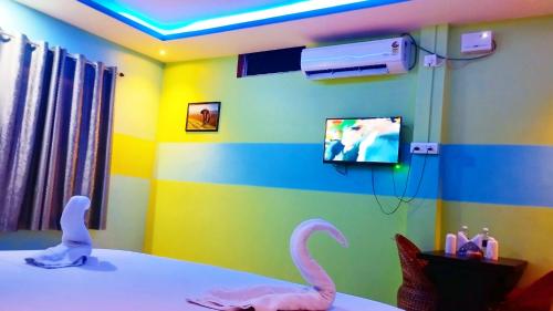 a room with a tv and two toy flamingos on a bed at The PugMark Wildlife Resort in Jyoti Gaon