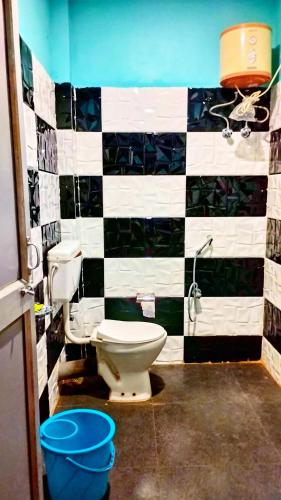 a bathroom with a toilet and a black and white tiled wall at The PugMark Wildlife Resort in Jyoti Gaon