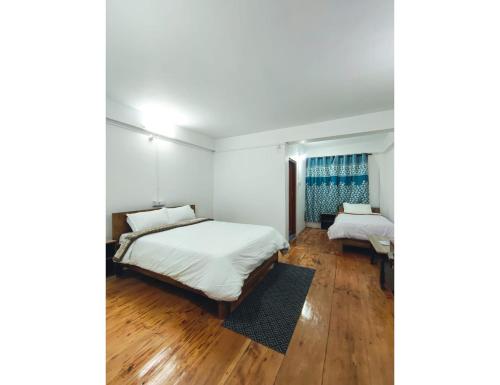 twee bedden in een kamer met houten vloeren bij Hotel Dawa Tawang, Arunachal Pradesh in Tawang