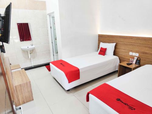 a hotel room with two beds and a television at RedDoorz near Prambanan Temple in Klaten
