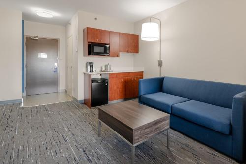 a living room with a blue couch and a kitchen at Holiday Inn Express Hotel & Suites-Edmonton South by IHG in Edmonton