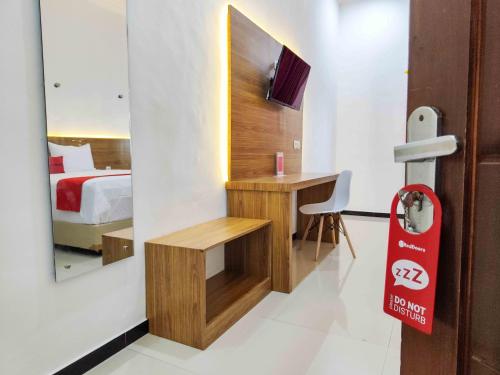 a bedroom with a bed and a desk and a mirror at RedDoorz near Prambanan Temple in Klaten