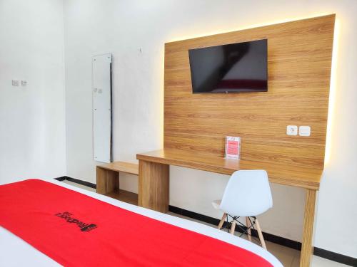 a bedroom with a bed and a television on a wall at RedDoorz near Prambanan Temple in Klaten