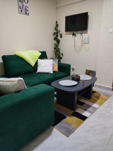 a living room with a green couch and a table at Elim apartment in Kitengela 