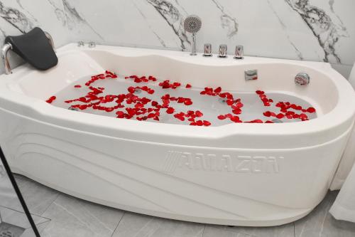 a bath tub filled with red flowers in a bathroom at Chemi Noi Bai Airport Hotel in Hanoi