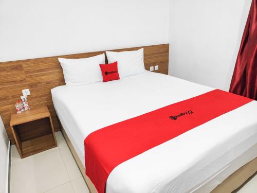 a bedroom with a white bed with a red blanket at RedDoorz near Prambanan Temple in Klaten