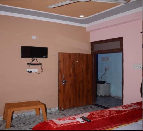 um quarto com uma cama e uma televisão na parede em HOTEL KRISHNA INN, NAINI em Prayagraj