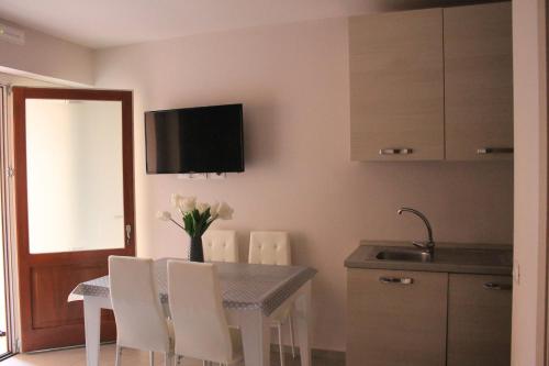 a kitchen with a table with white chairs and a television on the wall at La Ponzianina in Spoleto