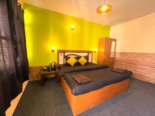 a bedroom with a bed with a yellow wall at Trippy Turtle Hostel in Manāli