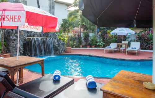 a swimming pool with a table and an umbrella at Silver Sands Sunshine - Angaara in Candolim