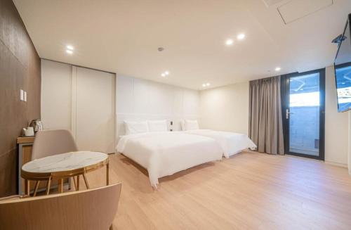 a bedroom with a large white bed and a table at H Moment Hotel Yeonsan in Busan