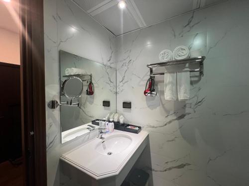 ein weißes Badezimmer mit einem Waschbecken und einem Spiegel in der Unterkunft A25 Hotel - 187 Trung Kính in Hanoi