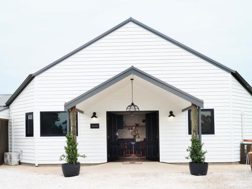 a white barn with a door and two plants at Shawwood Estate in Mudgee