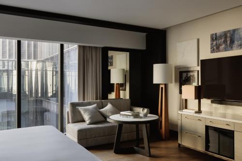 a hotel room with a bed and a couch and a tv at Capella Sydney in Sydney