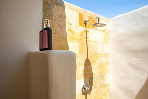 a shower in a bathroom with a tank on a wall at La Roja Bungalows in Nusa Penida