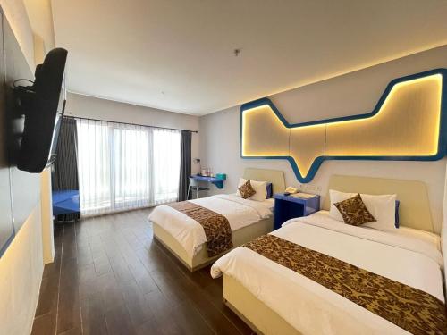 een hotelkamer met 2 bedden en een flatscreen-tv bij Golden Palace Hotel in Batu Merah