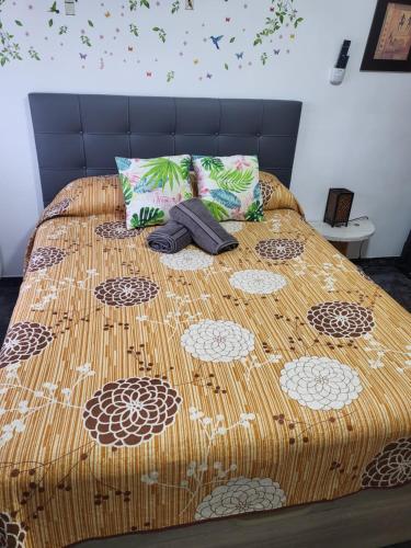 1 cama con edredón marrón y 2 almohadas en Casa Rural Oasis, una casa rural en Puertollano, agradable, con Piscina en zona tranquila, en Puertollano