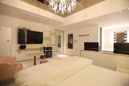 a bedroom with a bed and a television and a piano at February Hotel SeongSeo in Daegu