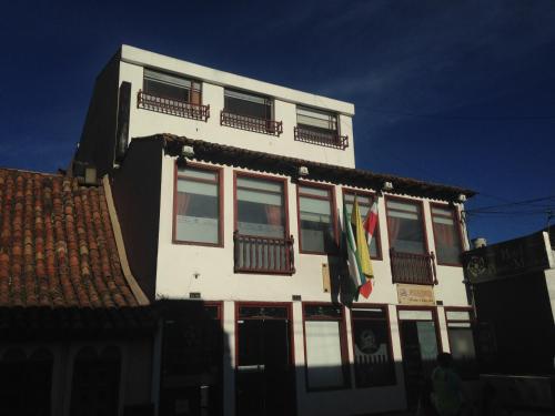 a white building with windows and flags on it at Hotel Plaza Muisca in Tunja