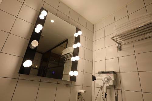 a mirror in a bathroom with a hair dryer and a camera at February Hotel SeongSeo in Daegu