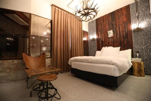 a bedroom with a bed and a chair and a chandelier at February Hotel SeongSeo in Daegu