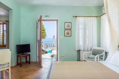 a bedroom with a bed and a tv and a window at Stolios in Skopelos Town