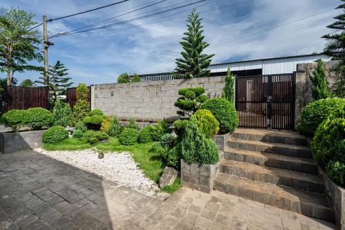 un jardín con una valla de piedra y arbustos en THE MYST VILLA BAO LOC en Ấp Tân Hà