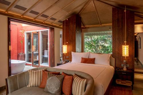 サワイ・マドプールにあるTaj Sawai,Ranthamboreのベッドルーム(ベッド1台、ソファ、バスタブ付)