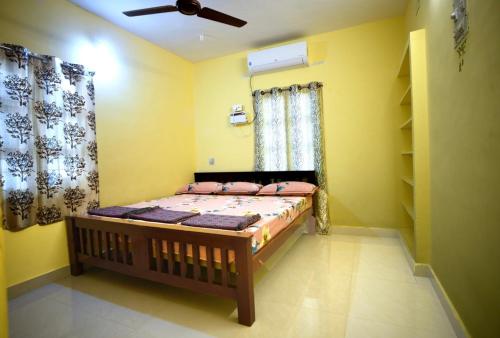 1 dormitorio con 1 cama en una habitación con paredes amarillas en AKC Holiday Home, en Tirunelveli