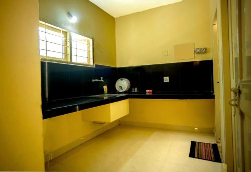 cocina con encimera negra y paredes amarillas en AKC Holiday Home, en Tirunelveli
