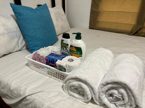 a basket of towels and toiletries on a bed at Cozy bedroom in Suva in Suva