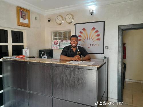 un hombre sentado en un mostrador en un restaurante en Winstons Place Hotel, en Onitsha
