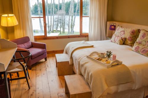 a bedroom with a bed and a chair and a window at La Escondida Casa De Huespedes & Spa in Villa La Angostura