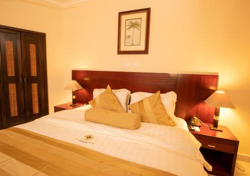 1 dormitorio con 1 cama grande con sábanas y almohadas blancas en La Palm Royal Beach Hotel en Accra