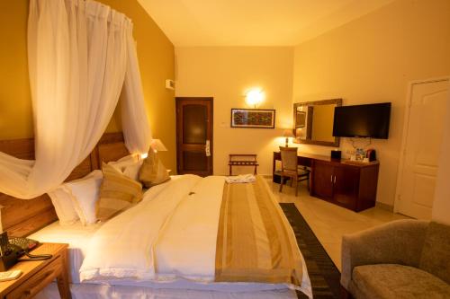 Schlafzimmer mit einem großen weißen Bett mit Vorhängen in der Unterkunft La Palm Royal Beach Hotel in Accra